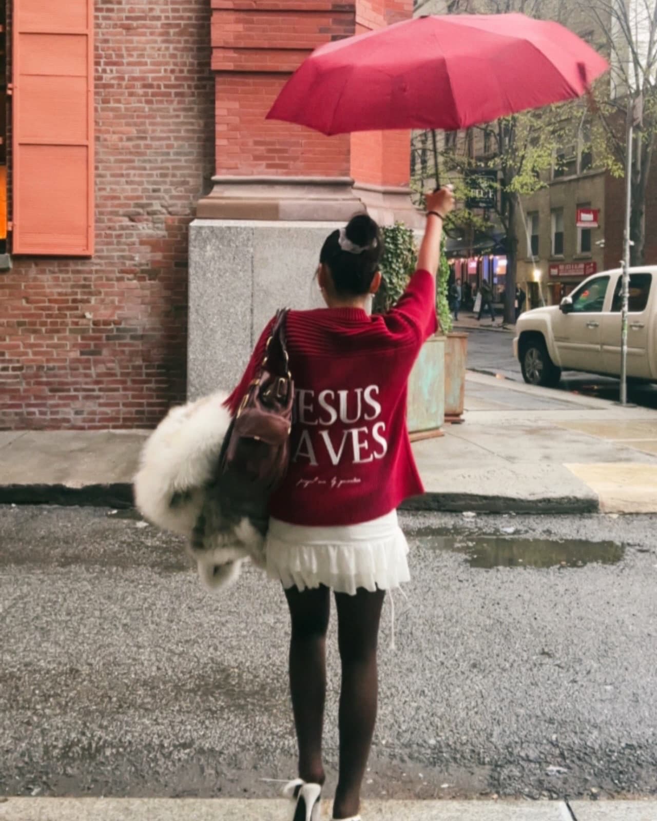 Mesmo em dias de chuva, a fé se manifesta. A mensagem "JESUS SAVES" (Jesus Salva) na blusa desta pessoa é um lembrete do poder transformador e da esperança que Cristo oferece.